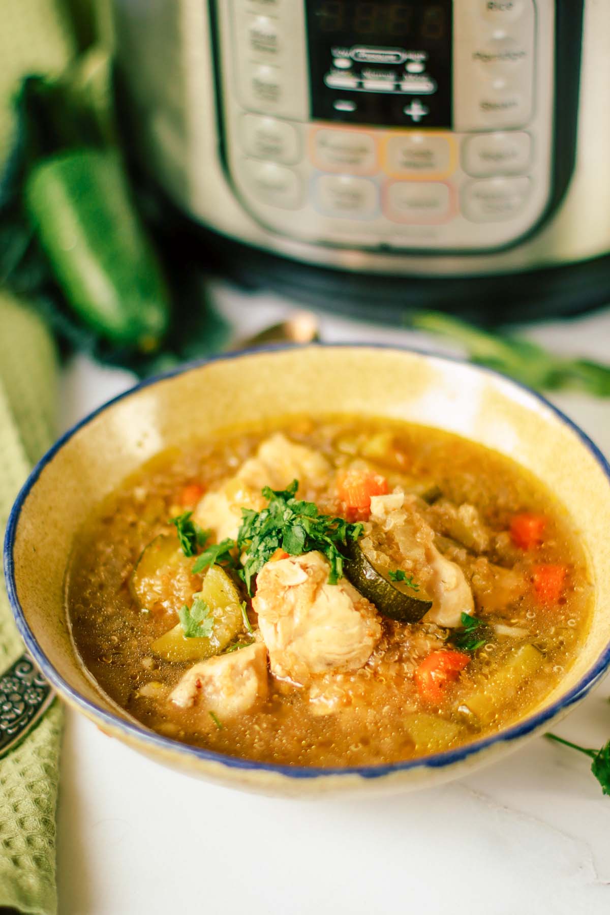 Quinoa soup in a bowl in front of the Instant Pot.