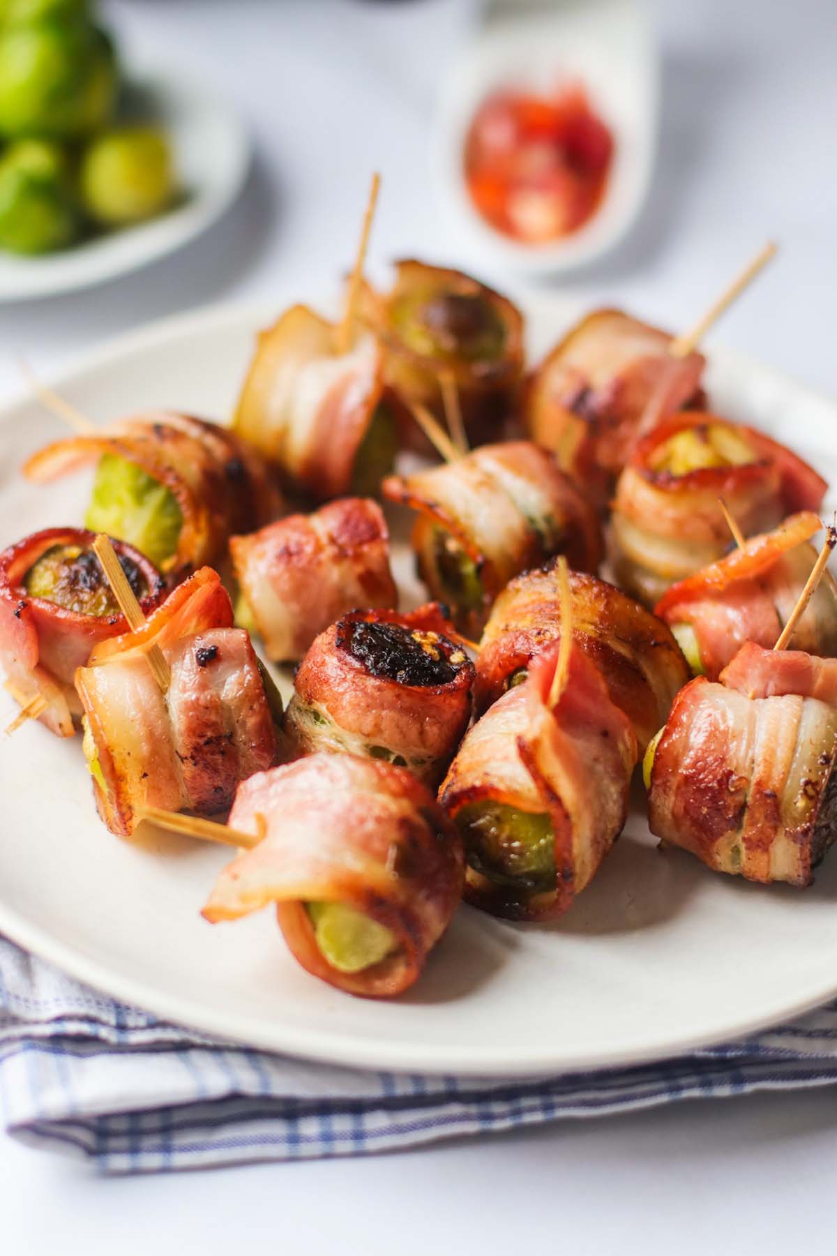 side view of bacon wrapped Brussels sprouts on a plate.