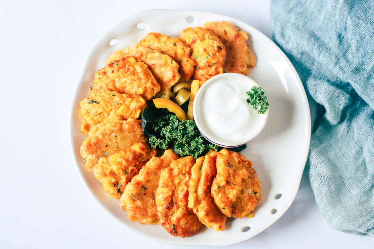 top view plate of corn fritters with a white dip.