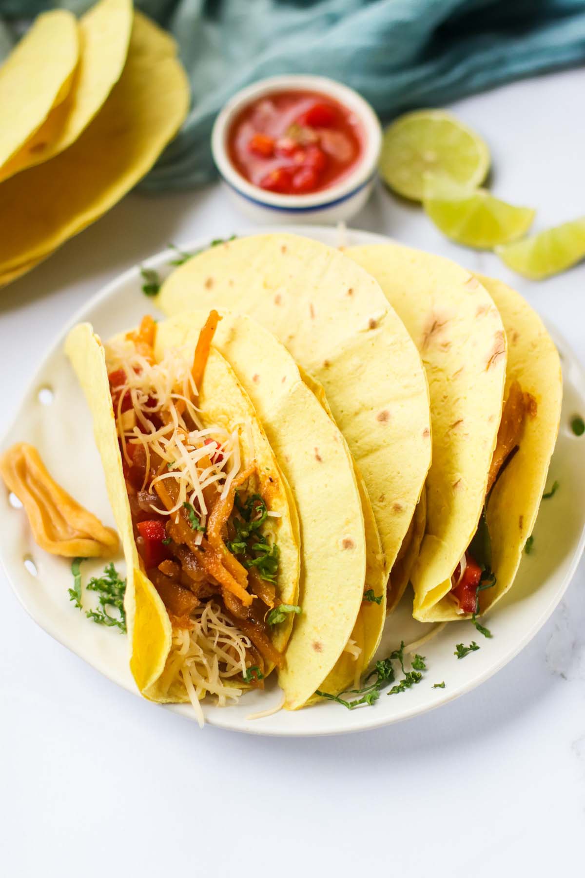 Tacos on a white plate garnished with chopped parsley.