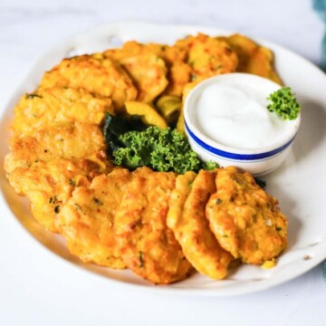corn fritters on a plate with a dipping sauce.