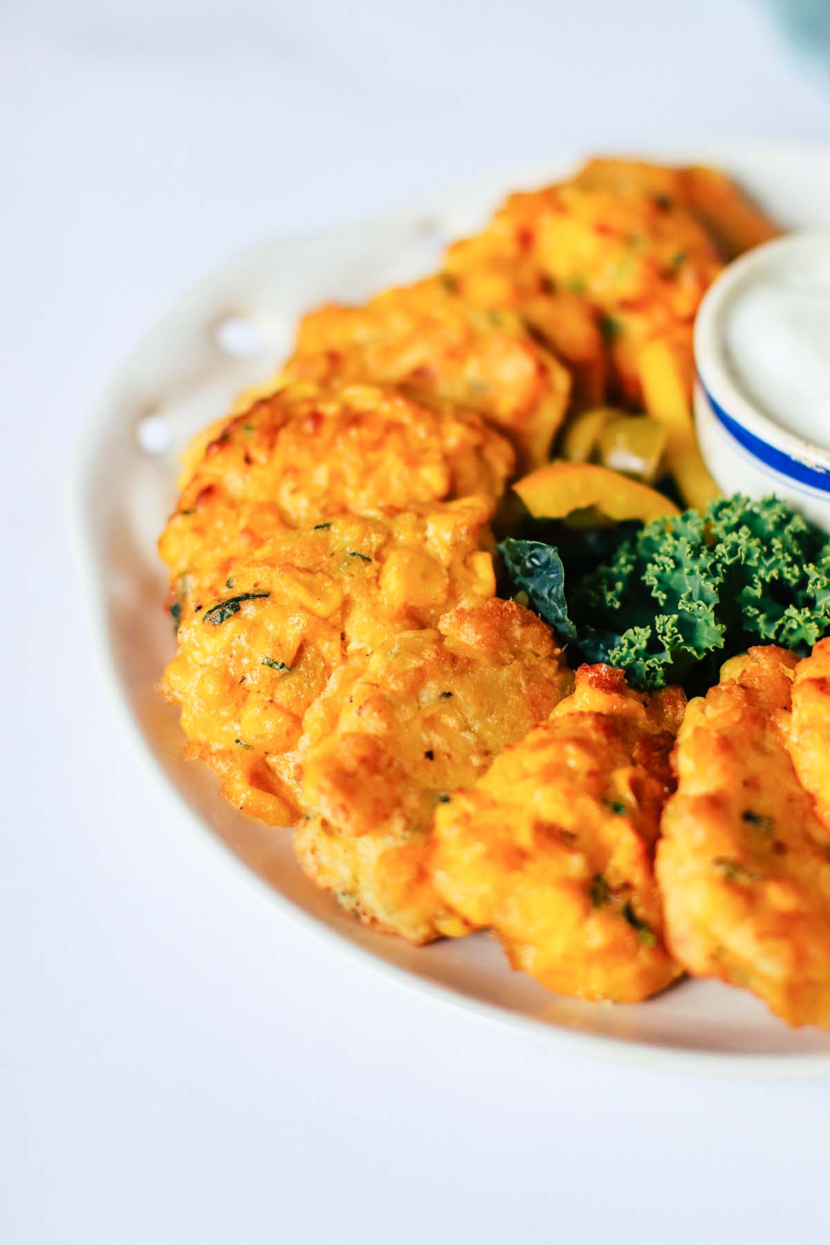 side view of corn fritters on a white plate.