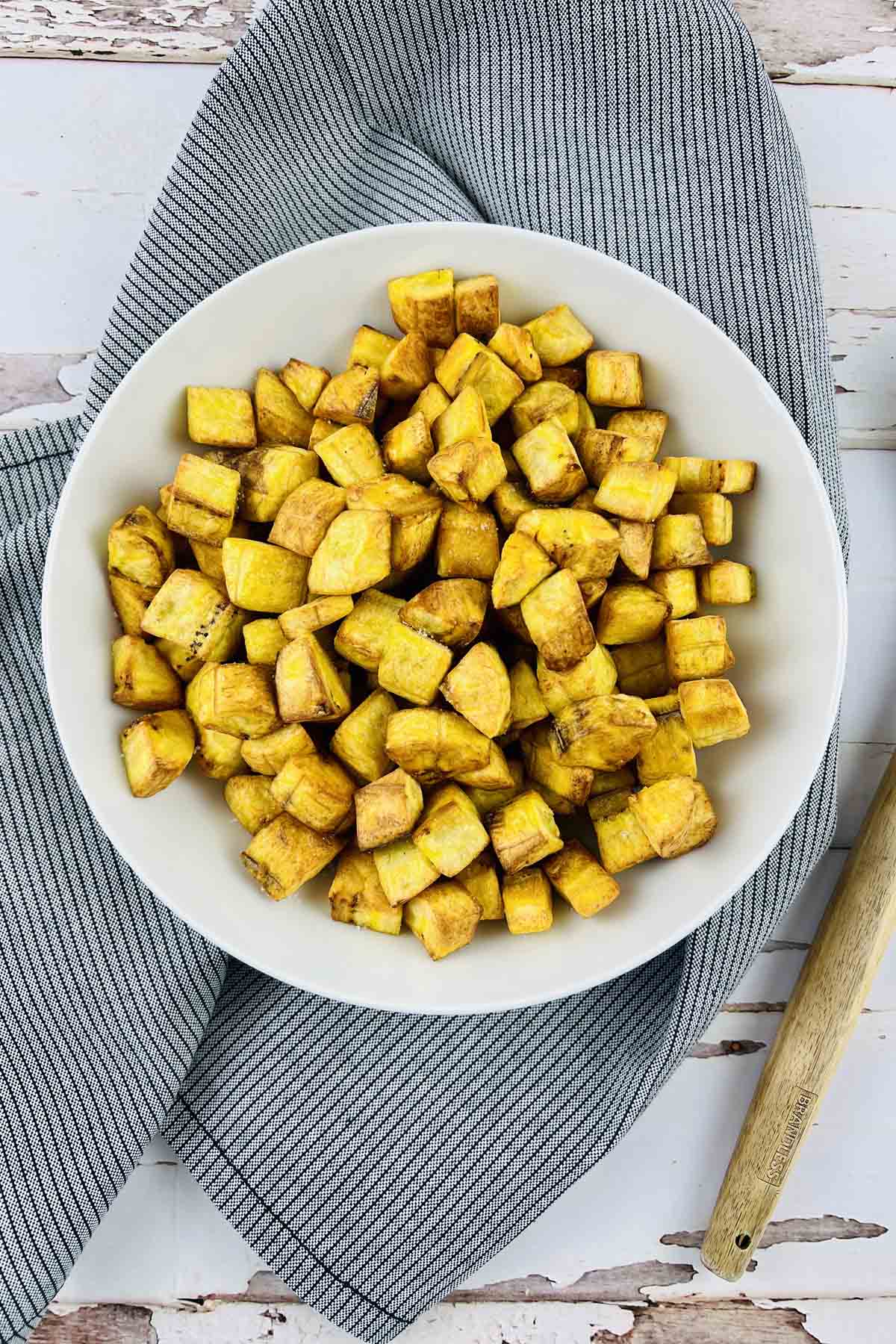 Croutons in a white bowl set on a blue kitchen towel.