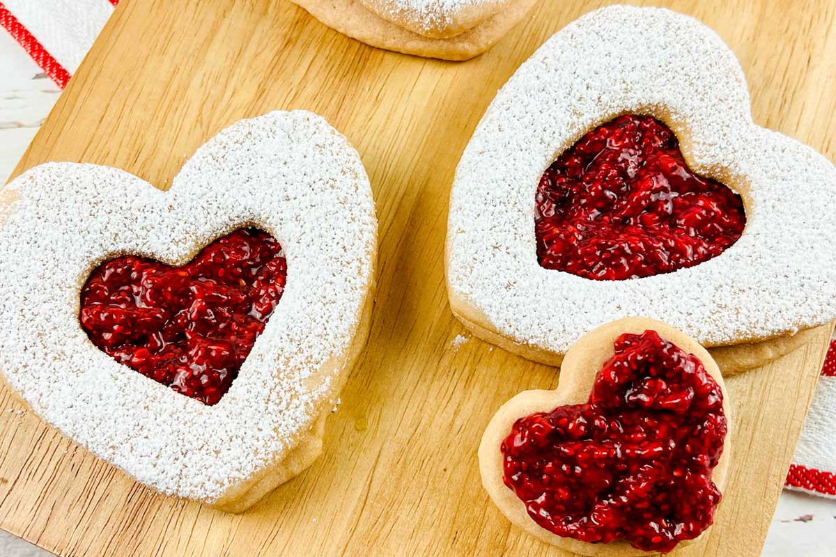 two heart shaped cookies on a cutting board.