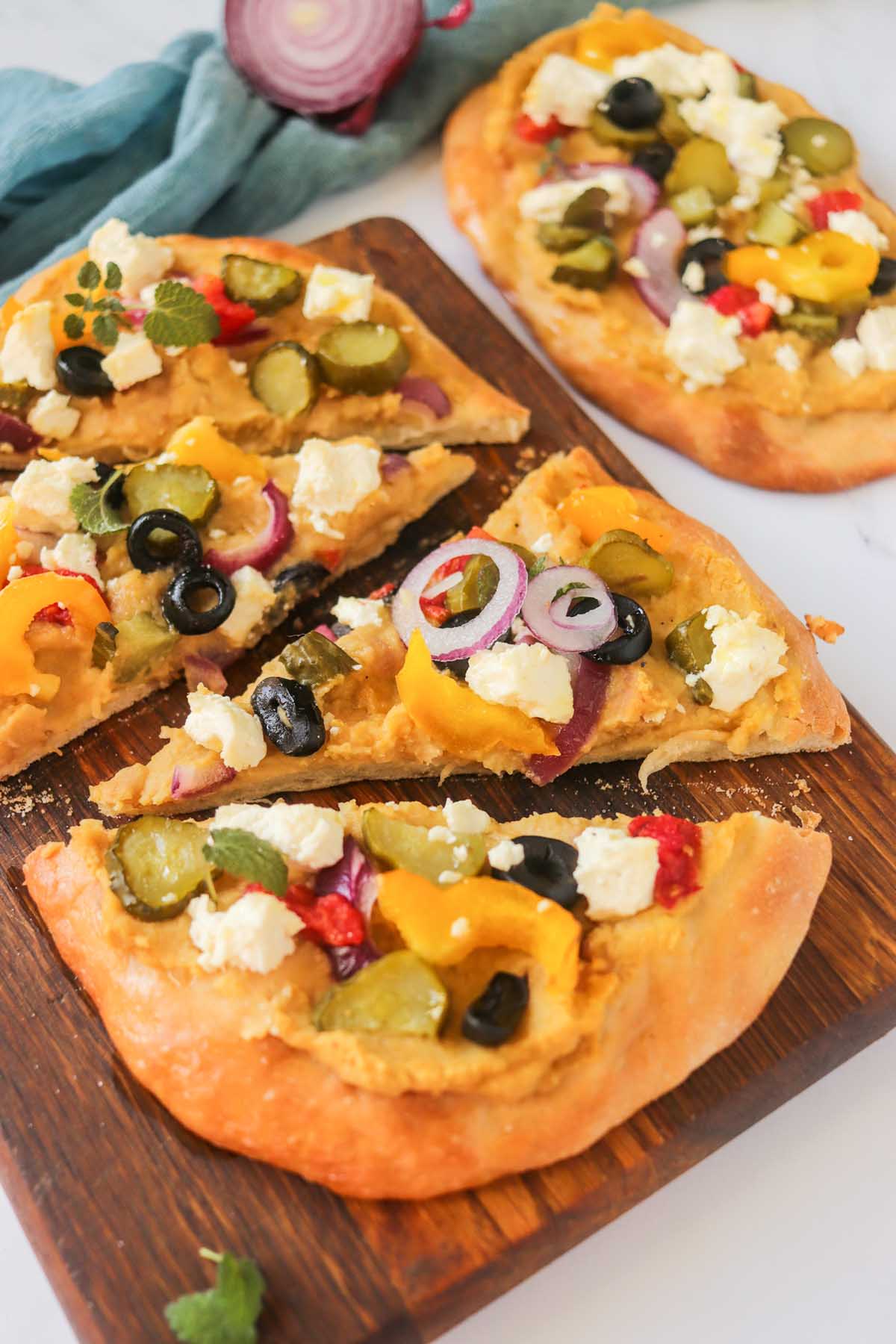 Naan pizza slices on a wood cutting board.