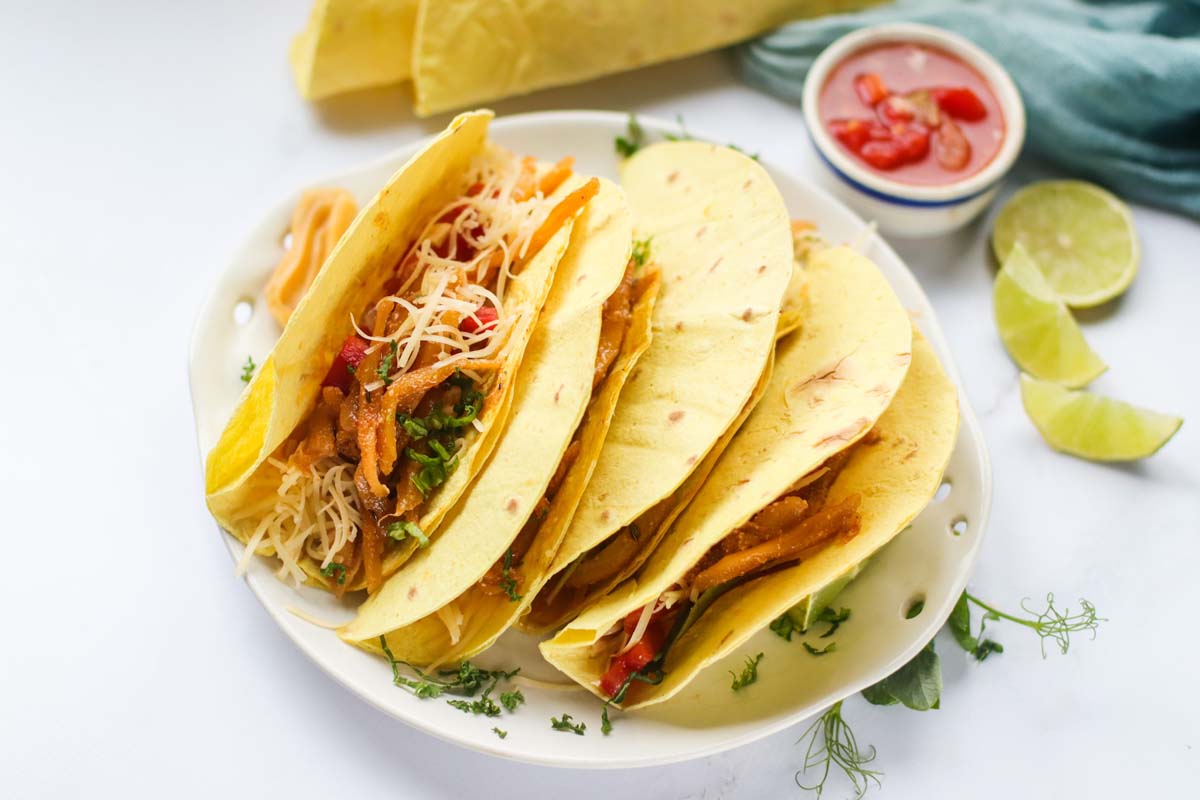 Tacos on a plate next to a bowl of salsa.