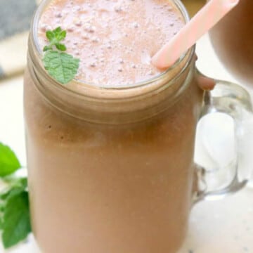 Chocolate shake in a glass with a pink straw.