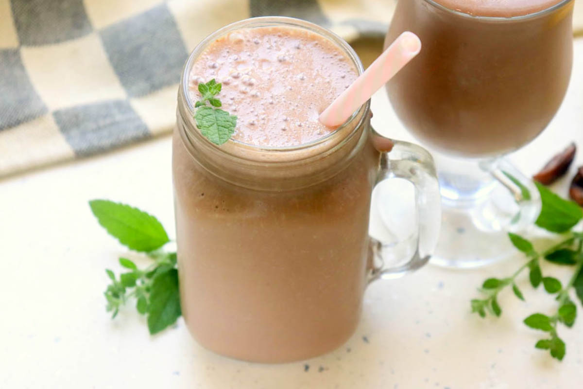 Chocolate shake in a glass with a pink straw.