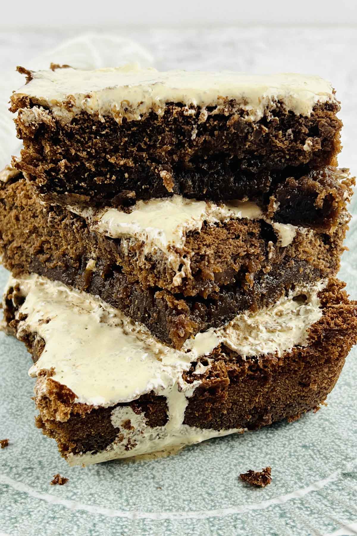 Three brownies stacked on a plate.