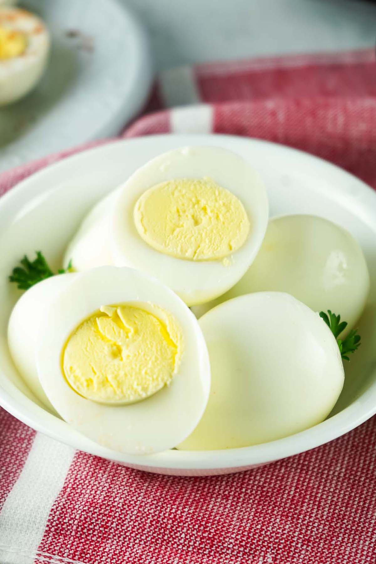 Boiled eggs in a bowl on a red towel.