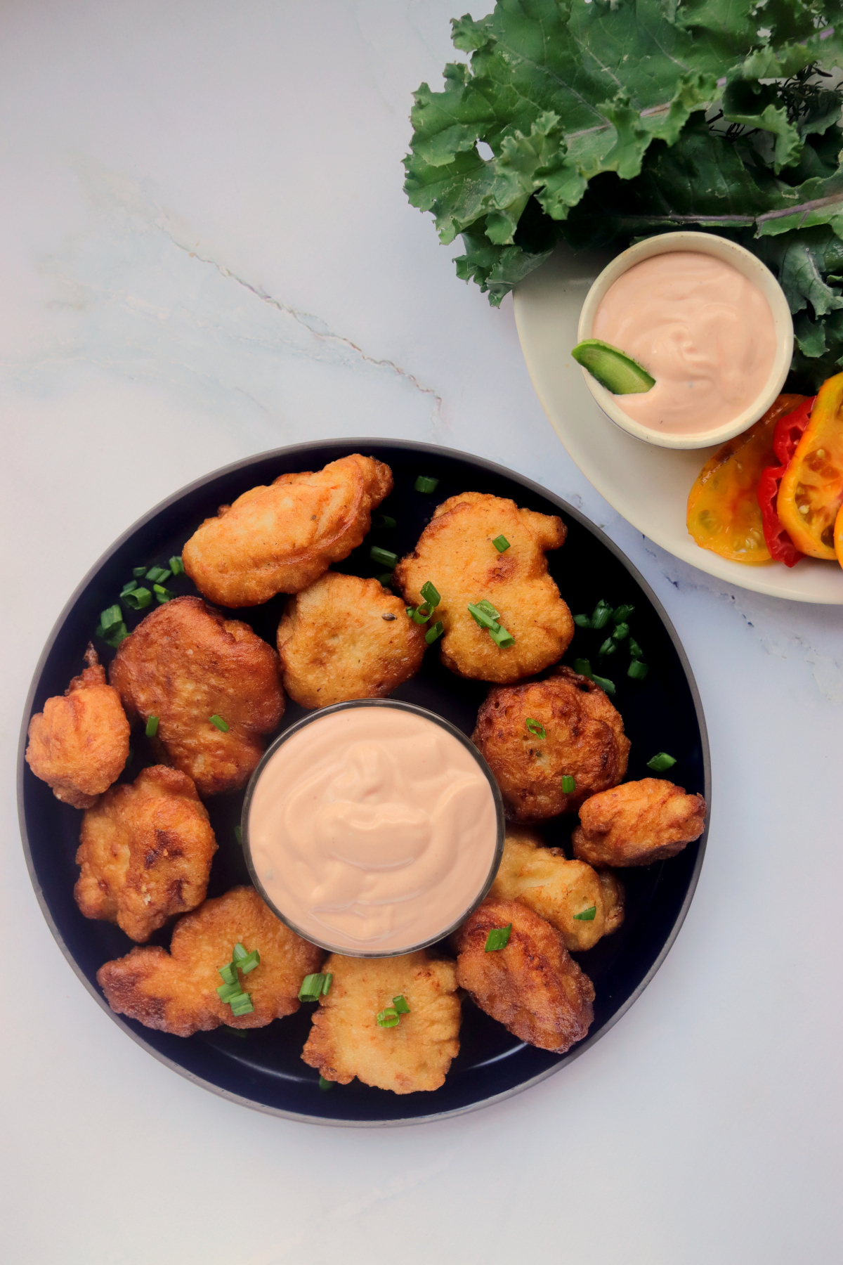 Sauce in a bowl on a plate of chicken nuggets.