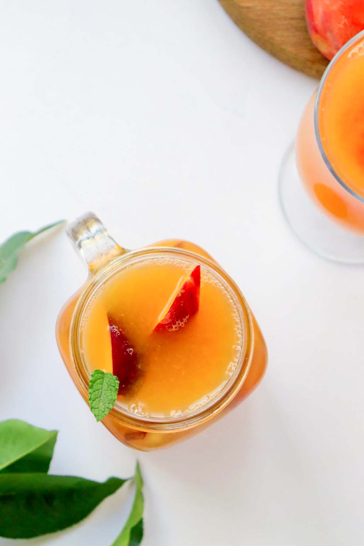 Iced tea in a glass with peach slices and mint.