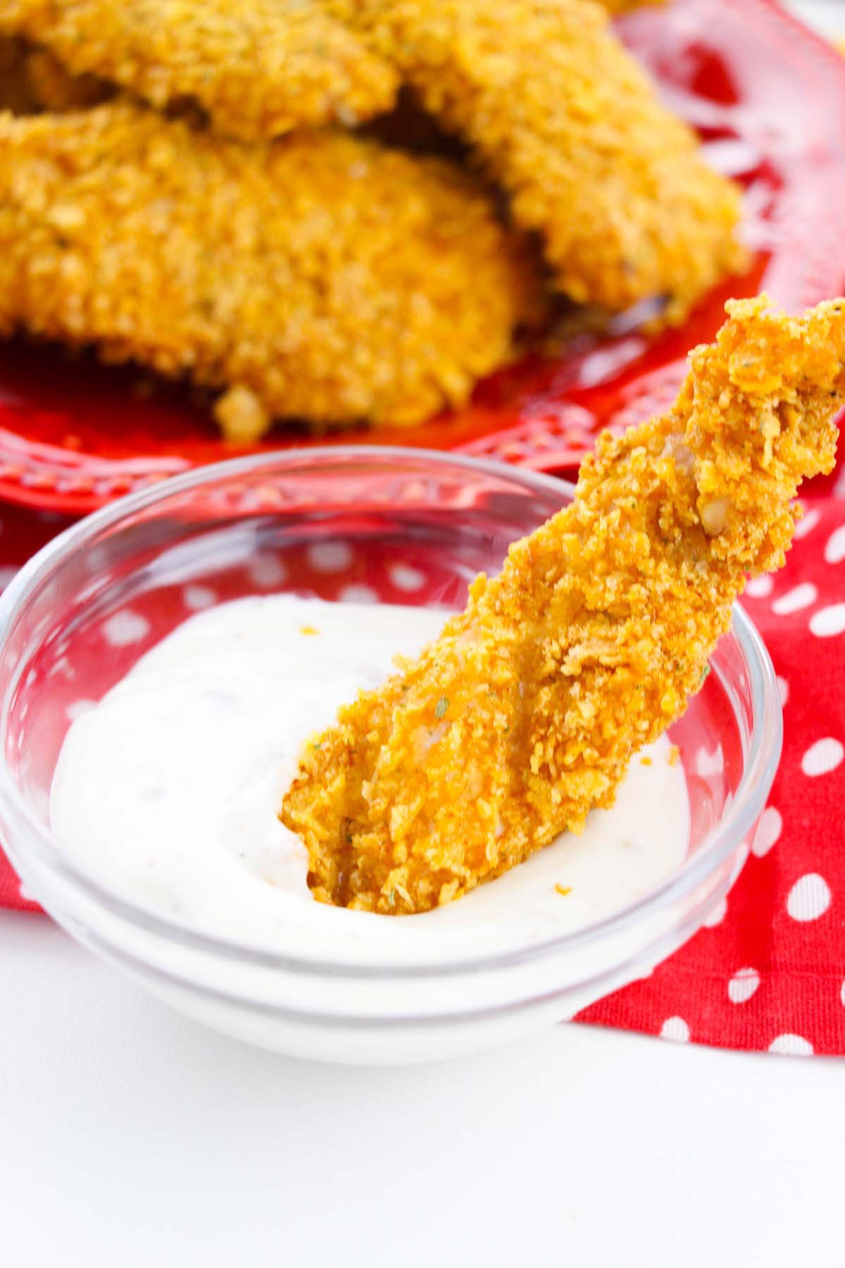 Chicken tender dipped in a bowl of ranch.