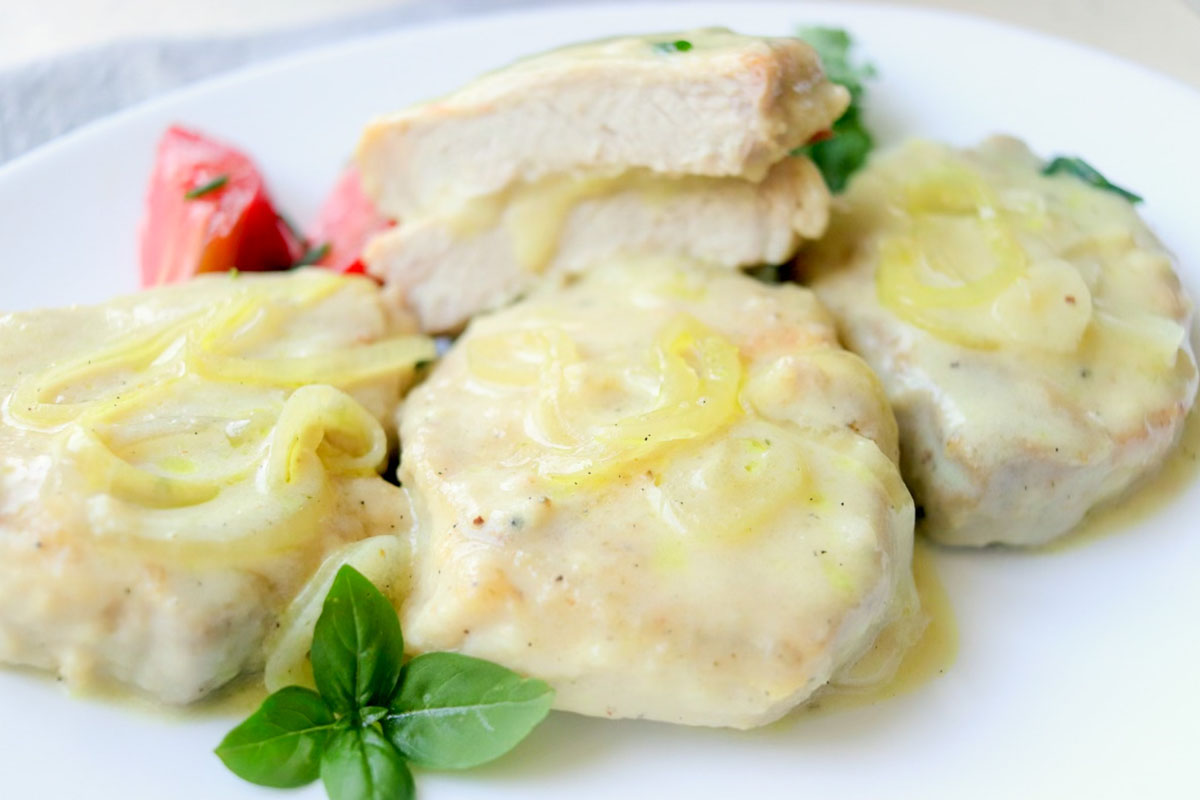 Pork chops on a plate and one is cut in half.