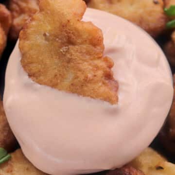 piece of chicken dipped in sauce.