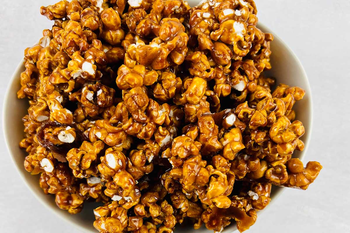 Caramel popcorn in a white bowl.