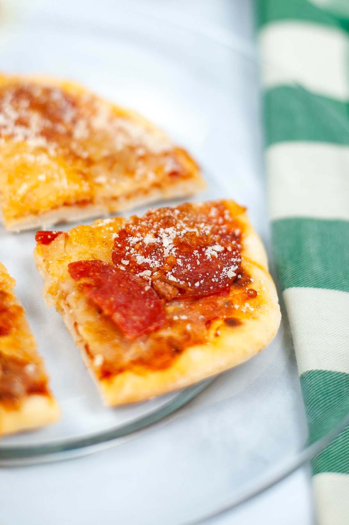 Slice of pepperoni pizza on a clear plate.