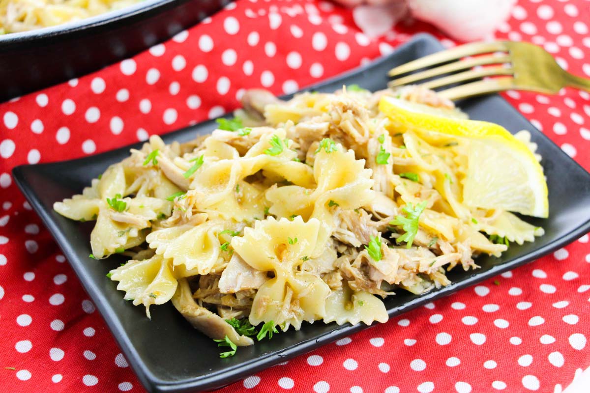 Chicken pasta on a black plate.