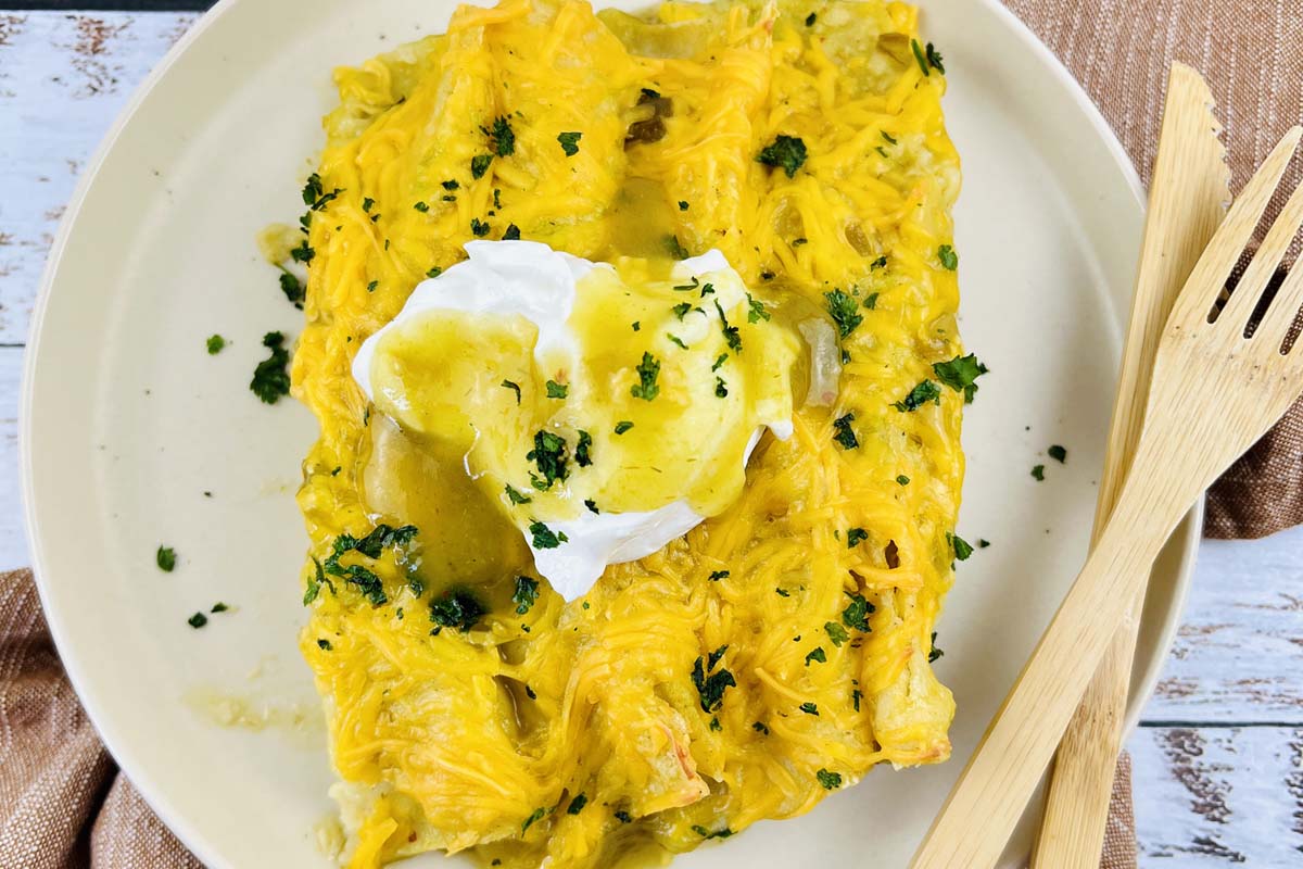 Enchiladas on a plate topped with sour cream.