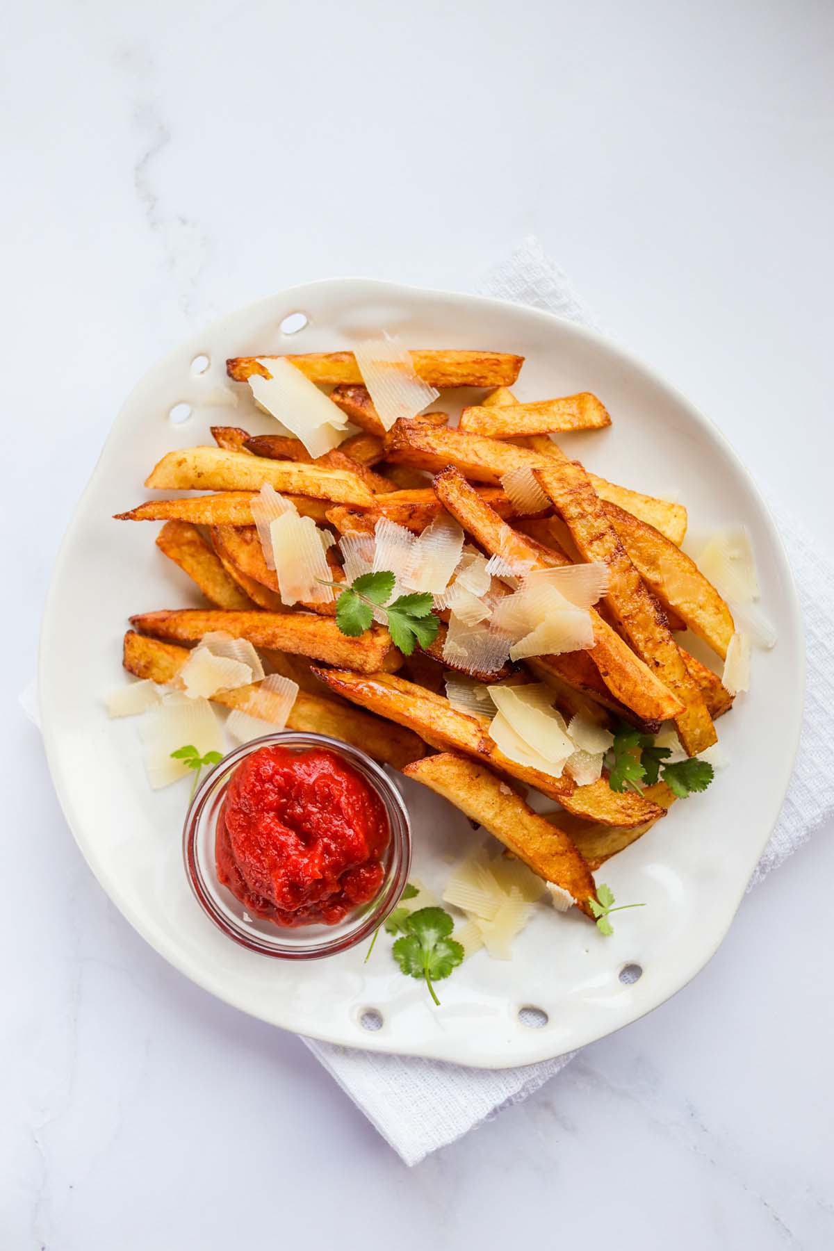 Fries on a plate topped with parmesan cheese and parsley.