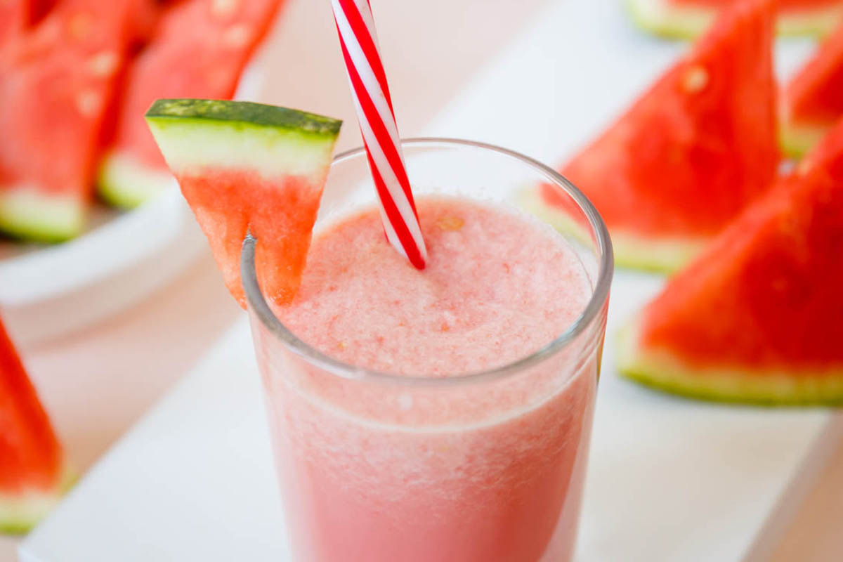 Milkshake in a glass with a watermelon wedge garnish.