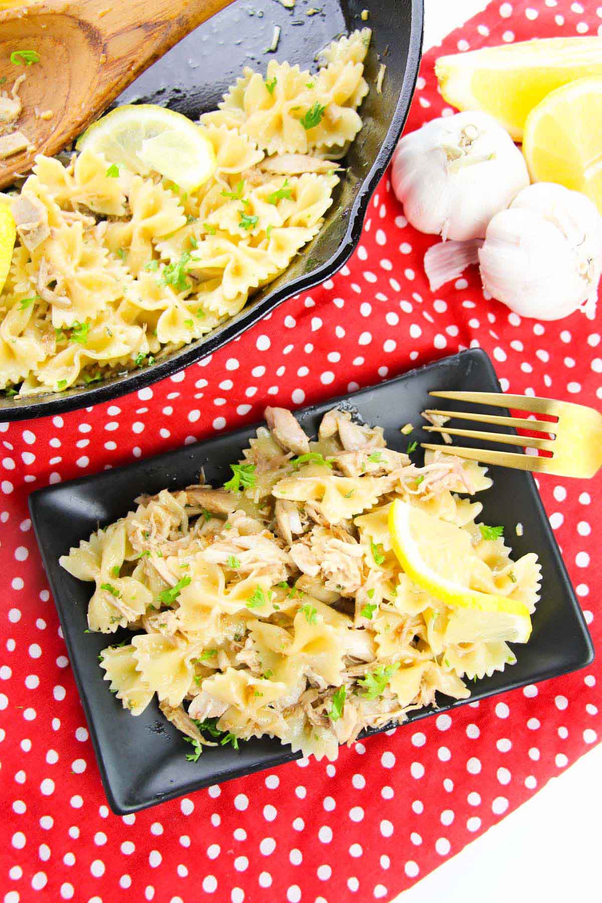 Pasta with lemon on a black plate.