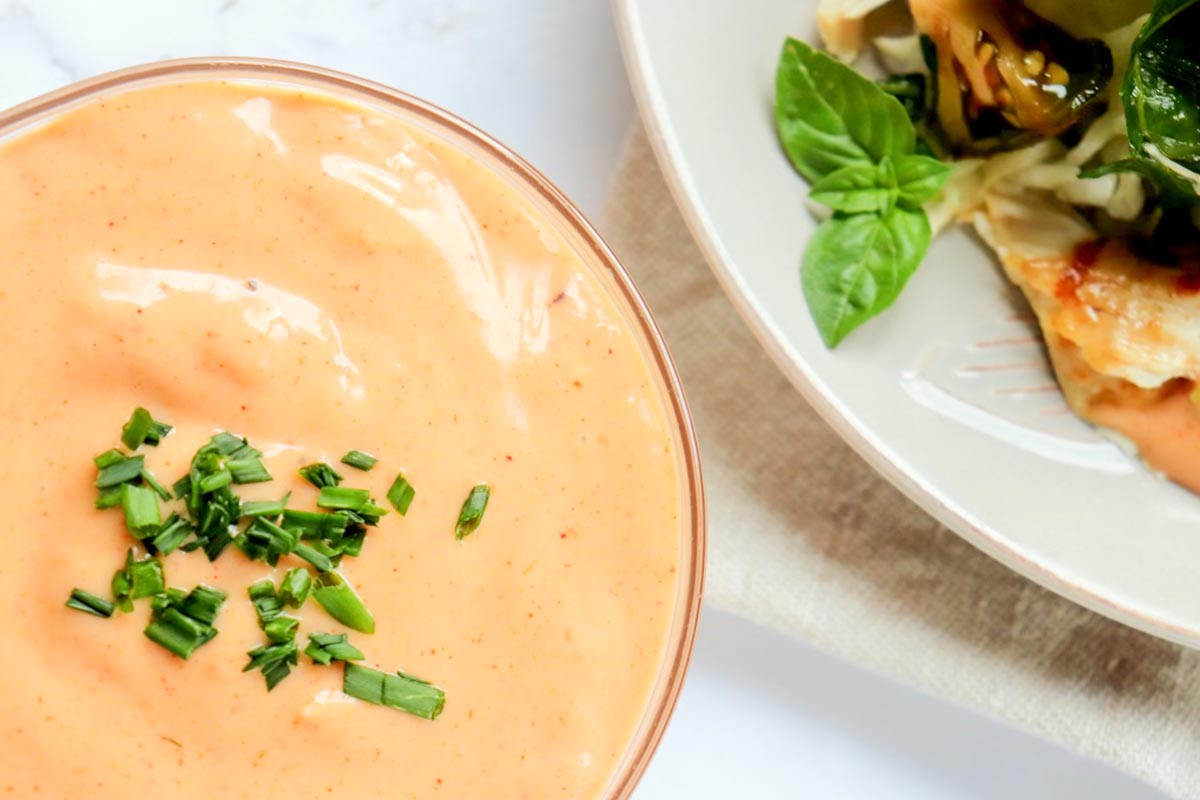 Dressing in a glass bowl topped with chives.