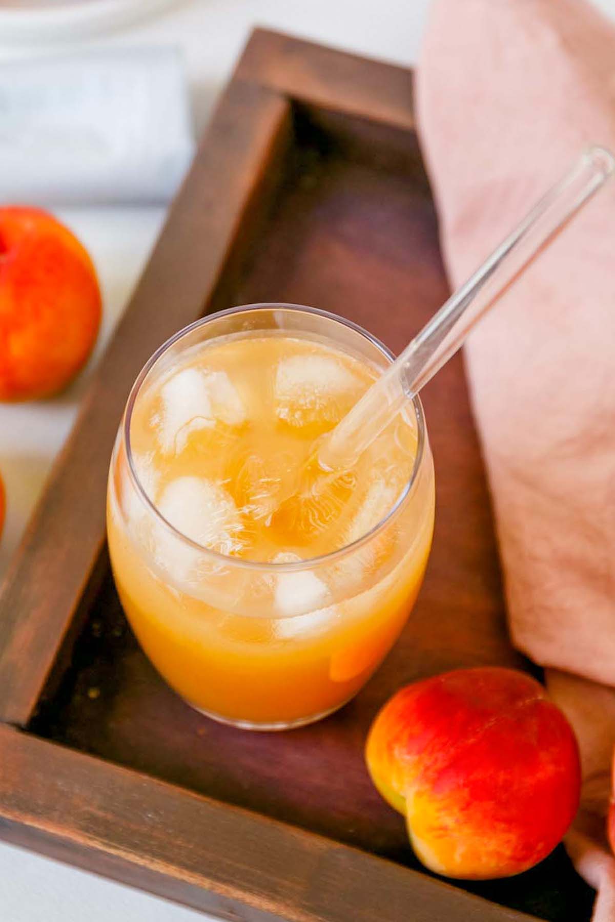 Glass of peach tea on a wood serving platter.