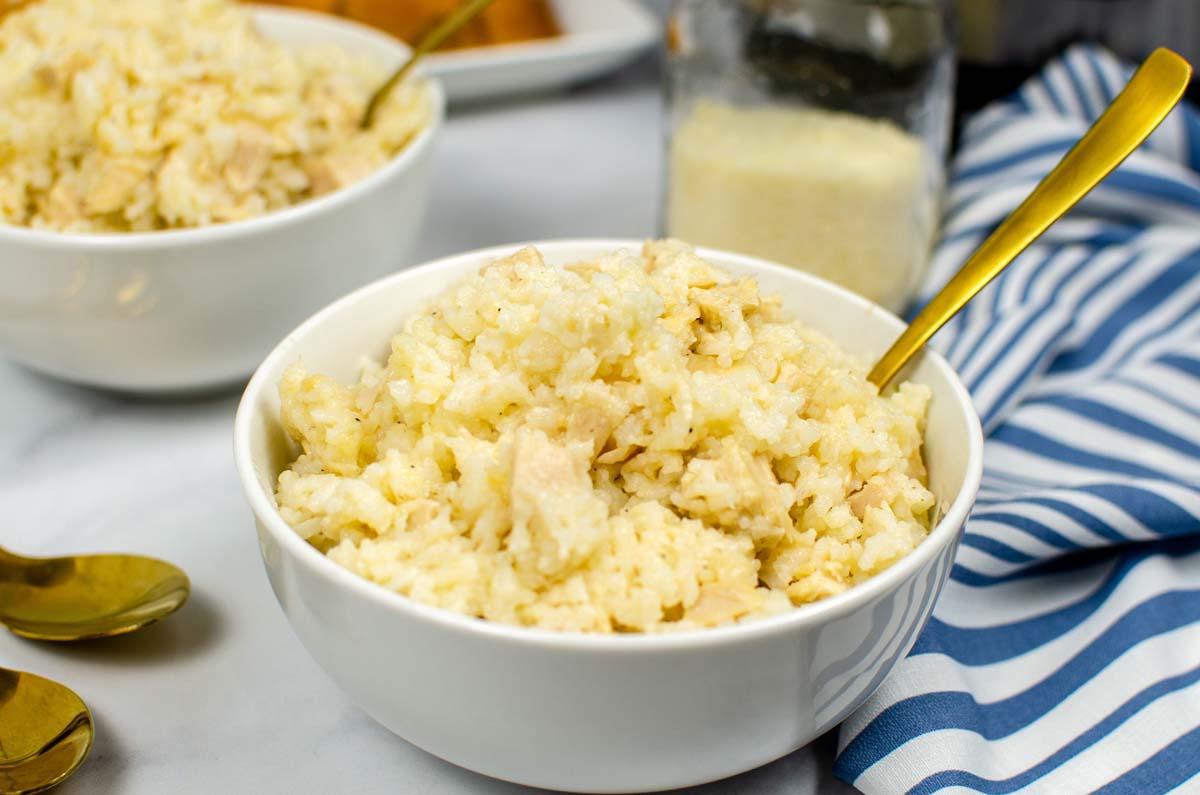 Rice and chicken in a bowl with a gold spoon.