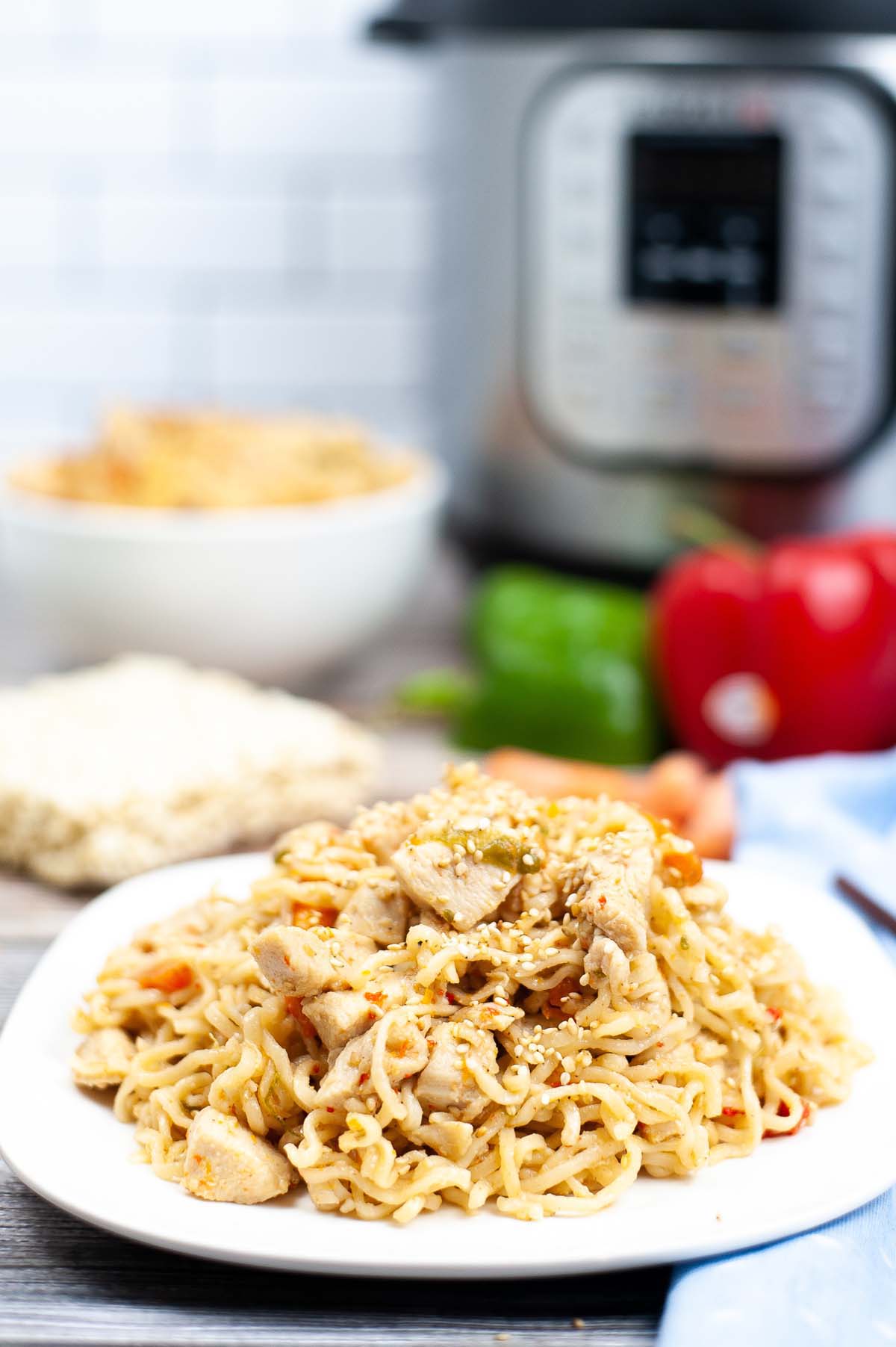 Ramen noodles topped with chicken on a white plate.