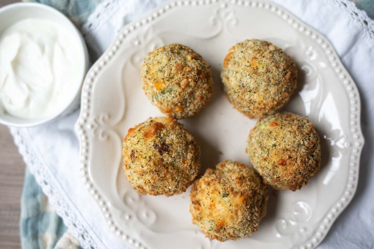 five mashed potato balls on a white plate.