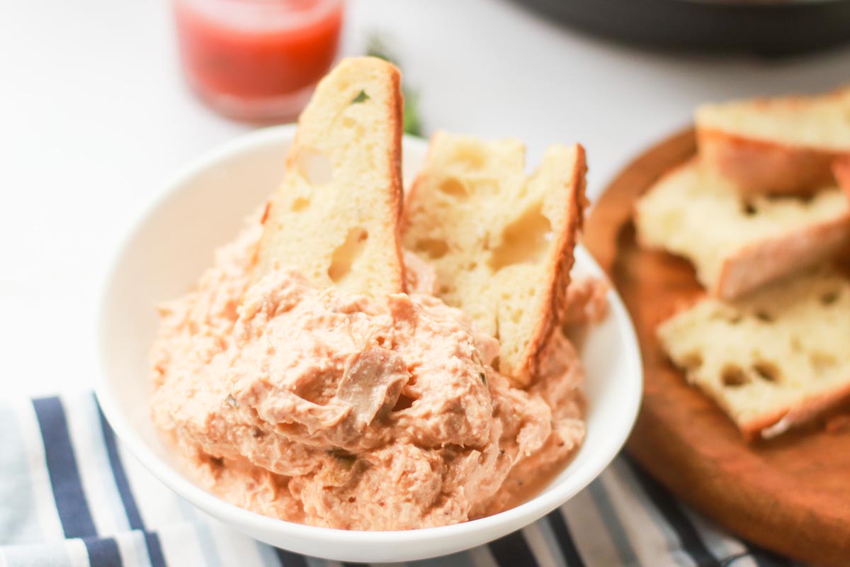 slices of bread in a bowl of chicken dip.