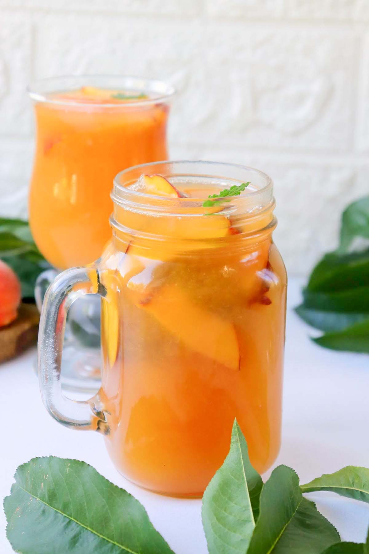 Peach tea in a jar with peach slices.