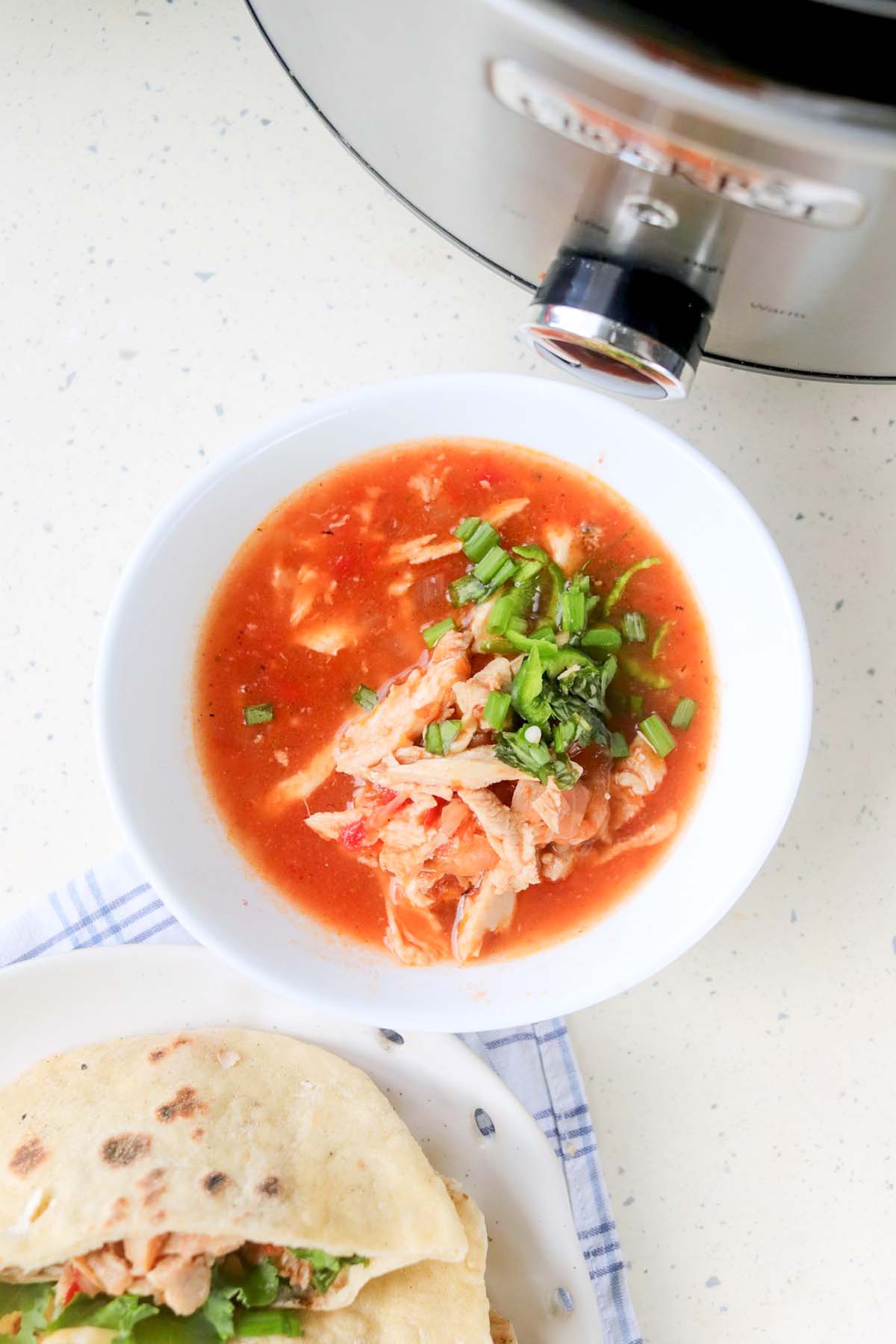 Shredded chicken in a bowl with red sauce.