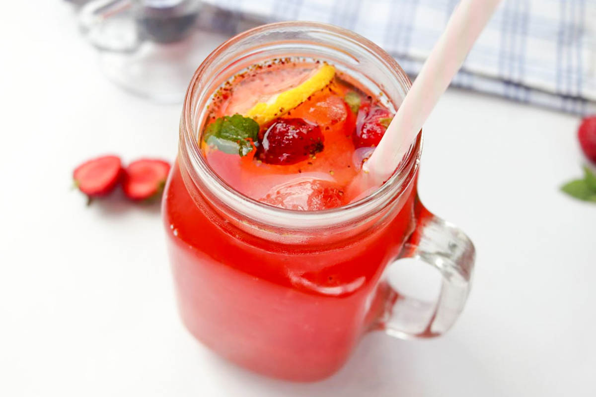 Tea lemonade in a glass with ice and a straw.