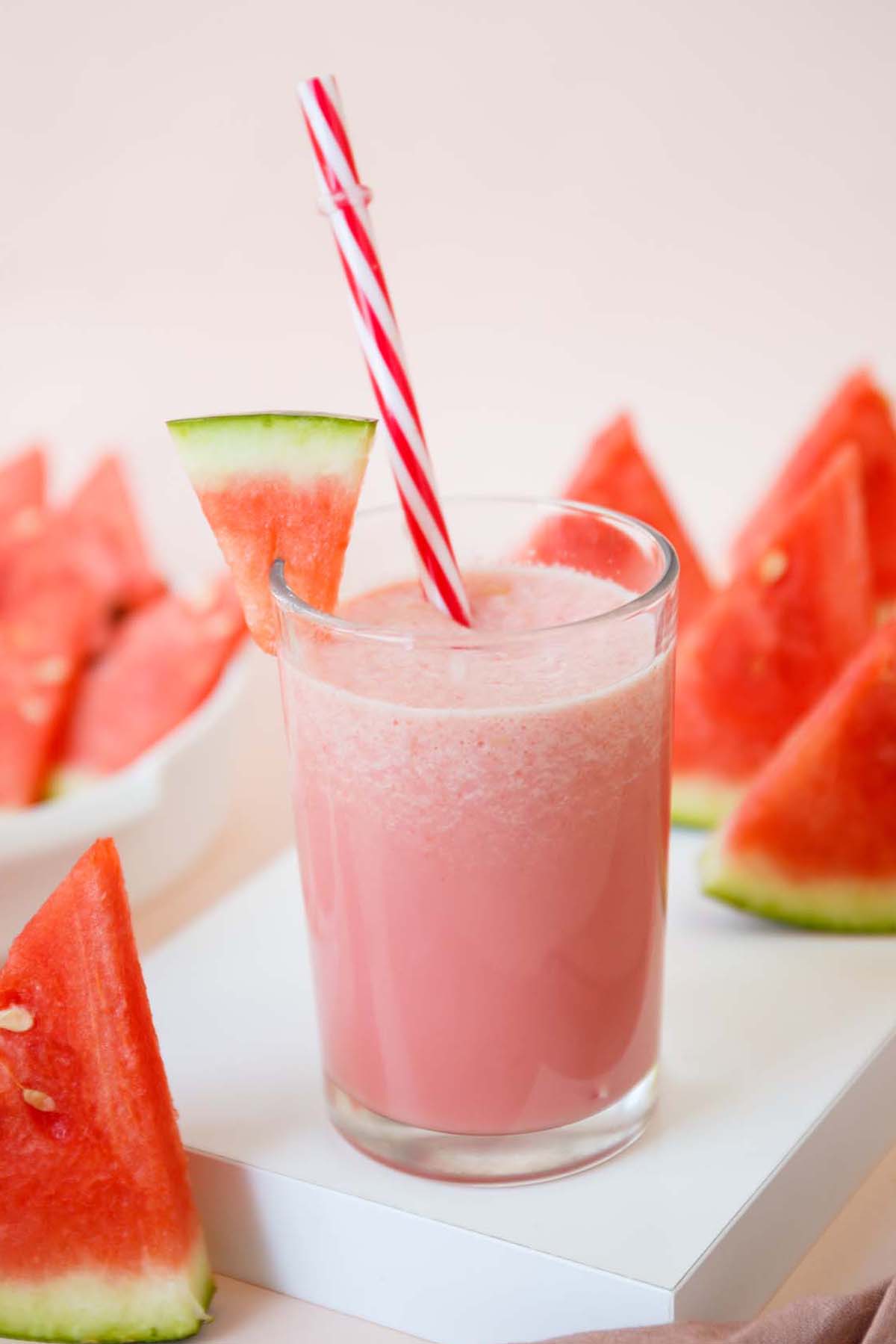 Watermelon milkshake in a glass with a red straw.