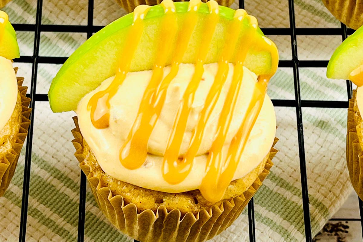 A cupcake topped with an apple slice and caramel drizzle.