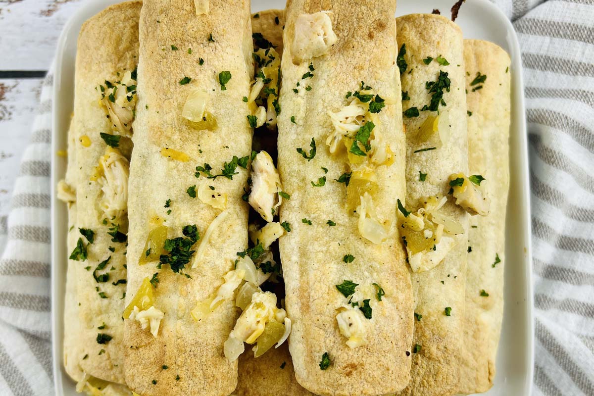 Taquitos stacked on a plate.