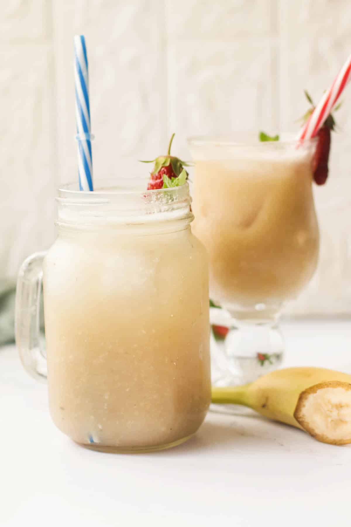 Two glasses of juice on a white table.