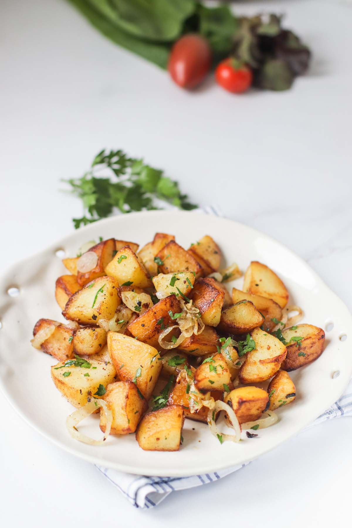 Fried potatoes on a plate that is set on a kitchen towel.