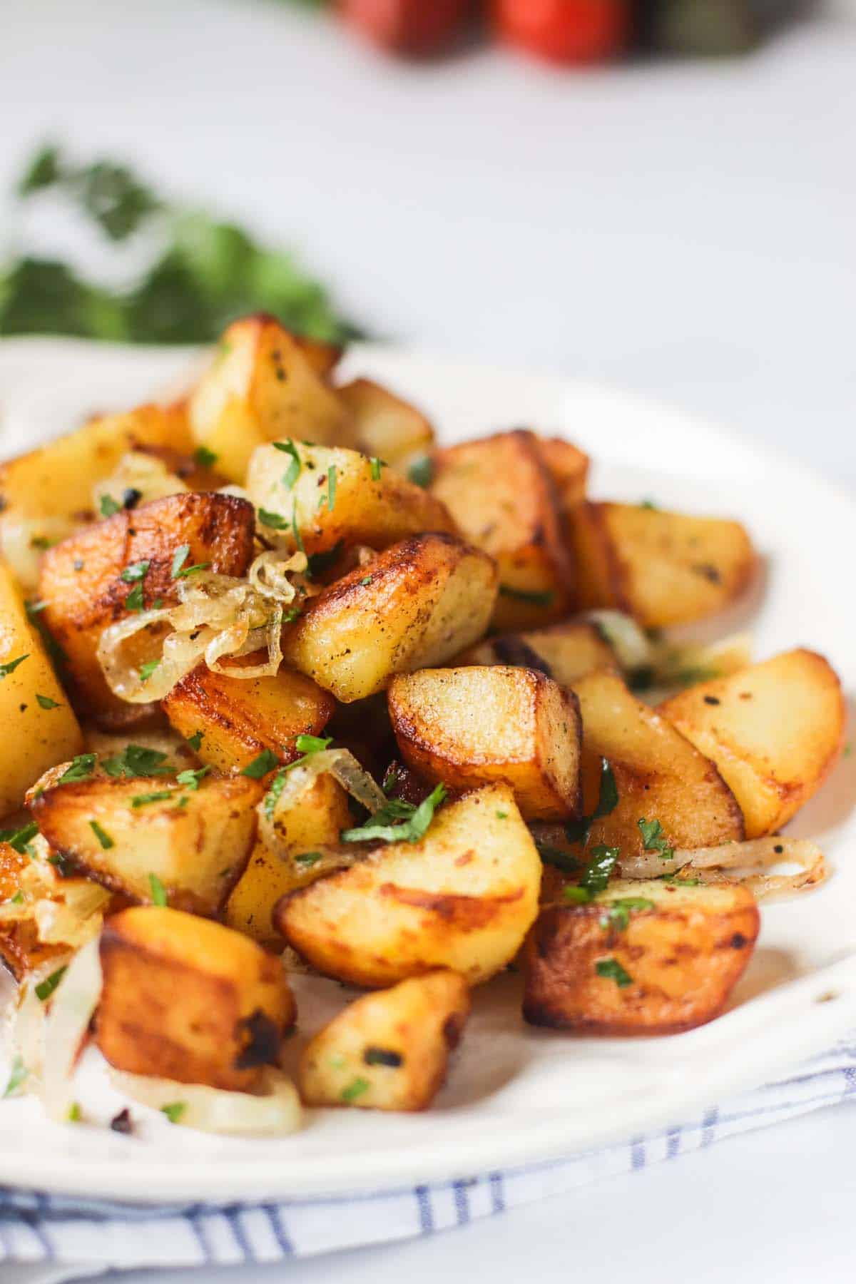 Fried potatoes on a plate topped with onions and parsley.
