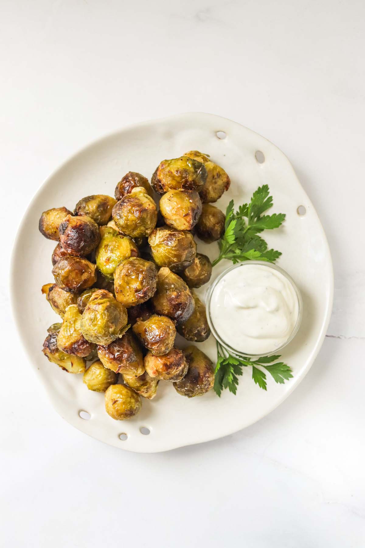 Brussels sprouts on a white plate garnished with parsley.