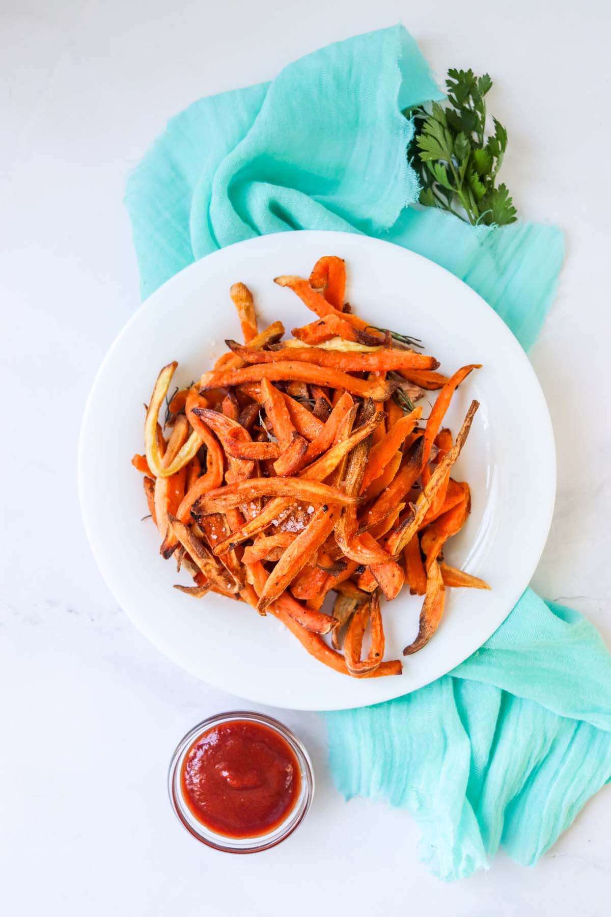 Fries on a white plate that is set on a blue kitchen towel.