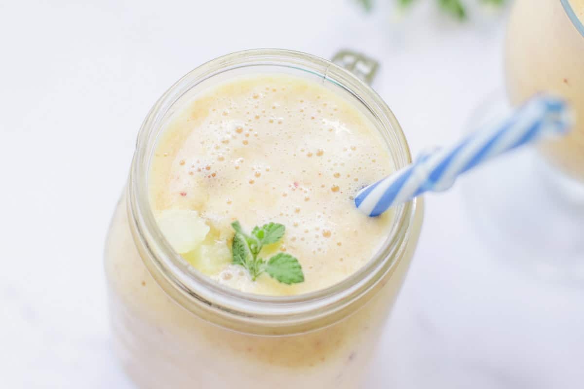 Smoothie in a glass jar topped with a mint leaf.
