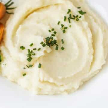 Mashed potatoes garnished with green herbs.