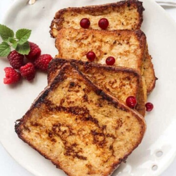 Four slices of French toast on a white plate.