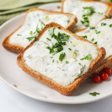 Garlic bread stacked on a white plate.
