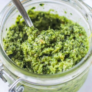 Pesto in a container with a spoon.