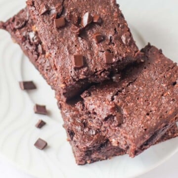 Brownies on a plate with chocolate chunks sprinkled over them.