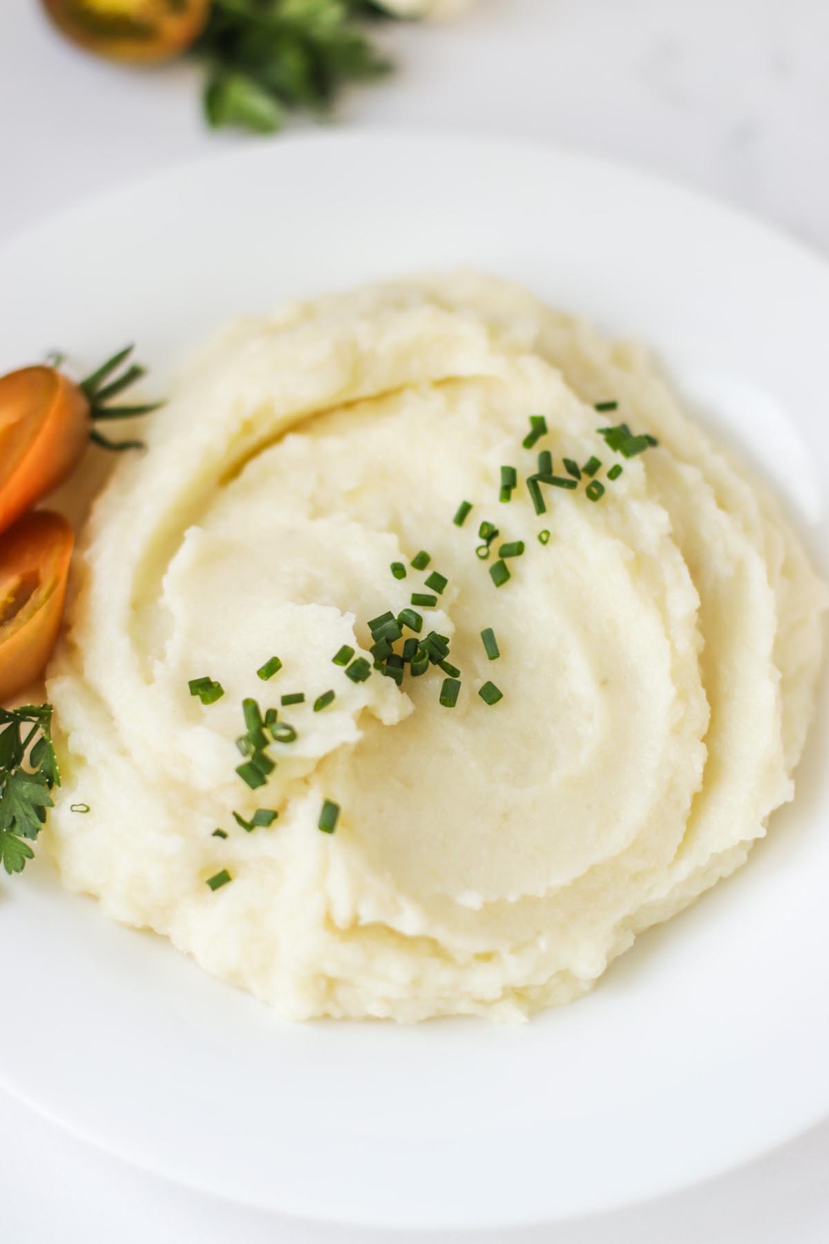Mashed potatoes garnished with green herbs.